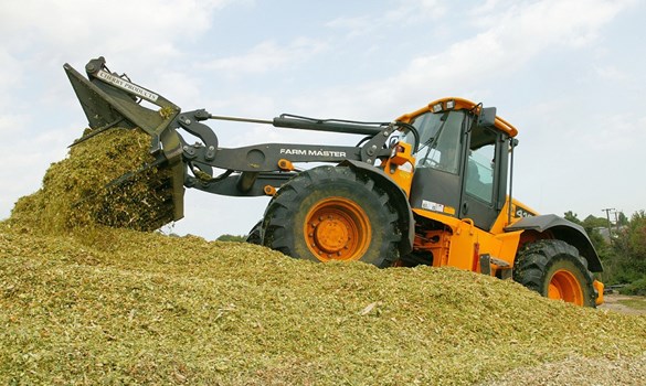 JCB wheel loader pouring maize into a silage clamp